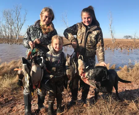 Youth girls holding waterfowl harvest while out on a hunt.