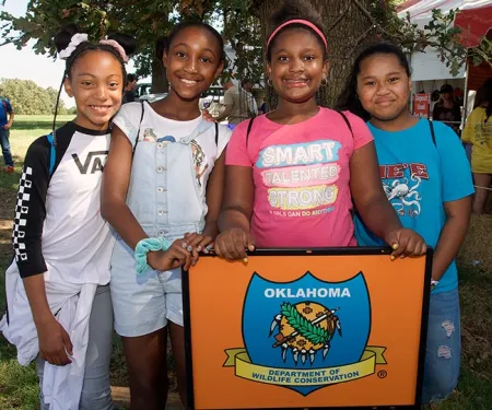 A group of young girls standing in front of a agency logo at Wildlife EXPO.
