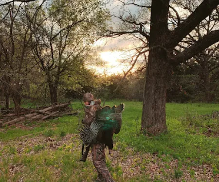 Turkey hunter in the field with turkey over shoulder.
