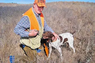 Man with dog and quail in the field.
