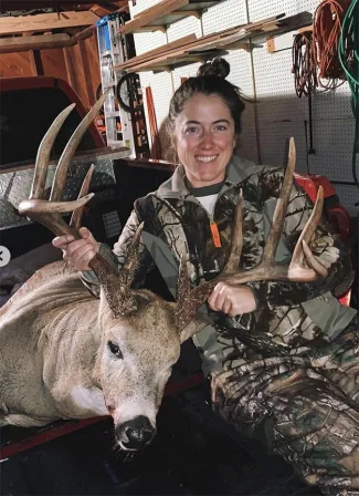 Allyssa Brown with harvested buck in a garage in the bed of a truck.