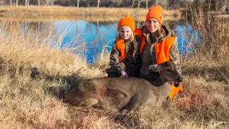 Woman and girl in the field with harvested doe.  Photo by Barry Bolton
