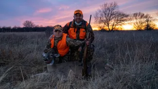 Father and son in the field with harvested doe, photo by Smokey Solis