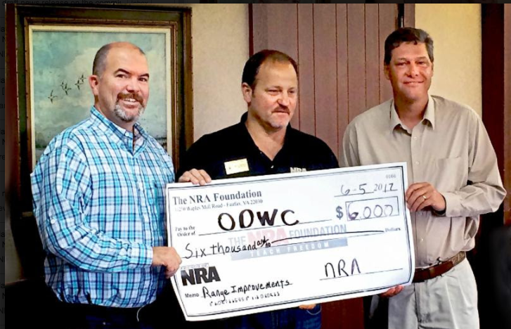Darren Delong, senior field representative for the National Rifle Association (center) presents a $6,000 donation for Lexington WMA shooting range renovations to Wildlife Department Director J.D. Strong (left) and Information and Education Chief Nels Rodefeld during the June meeting of the Oklahoma Wildlife Conservation Commission at Woolaroc near Bartlesville.  (DON P. BROWN / ODWC)