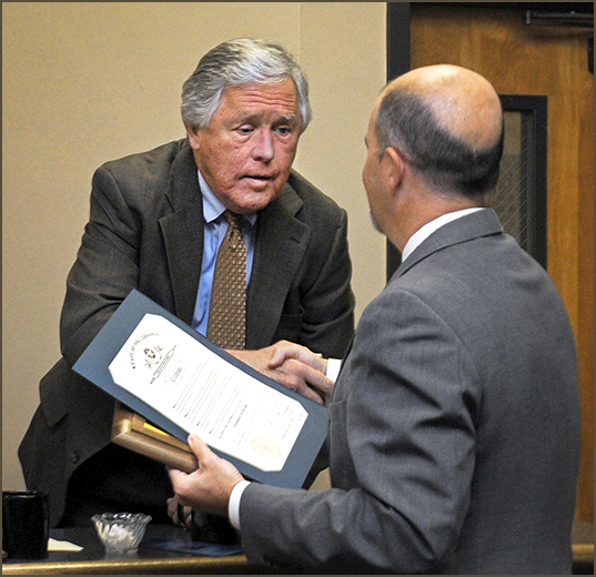 Wildlife Conservation Commissioner Ed Abel receives congratulations for his 16 years of service from Wildlife Department Director J.D. Strong. Abel will complete his term in June.