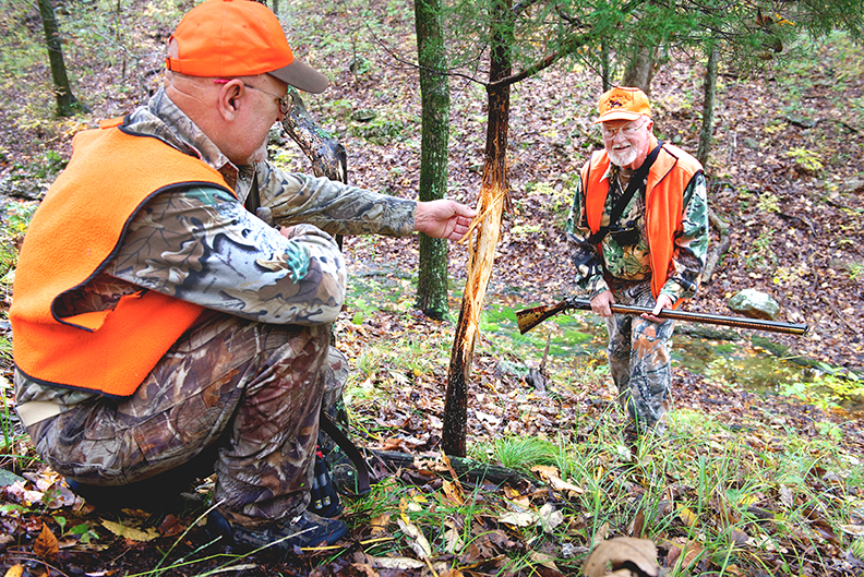 Scouting for deer sign, these muzzleloader hunters have discovered a rub in the area they intend to hunt.
