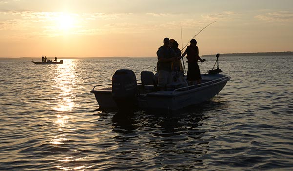 Boat on the water with sunset in the background.