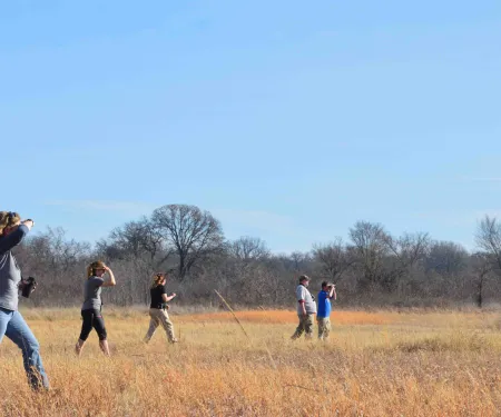 People walk through field surveying.