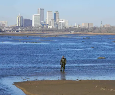Biologist stands in Arkansas River near downtown Tulsa.