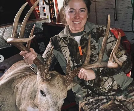 Allyssa Brown with harvested buck in a garage in the bed of a truck.