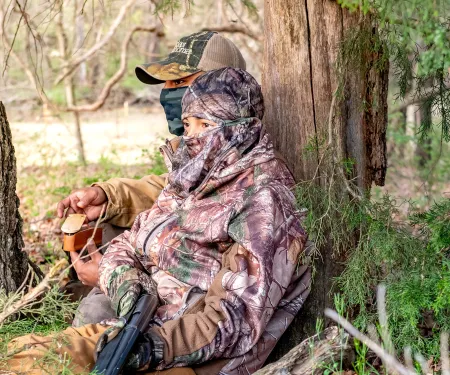Two turkey hunters sitting under a tree.  Photo by Kelly Adams