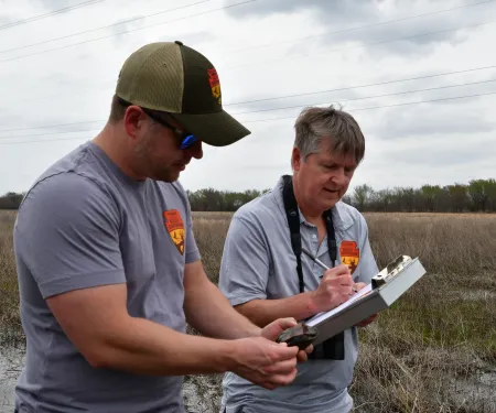 Two biologists look at a small turtle and record its location. 