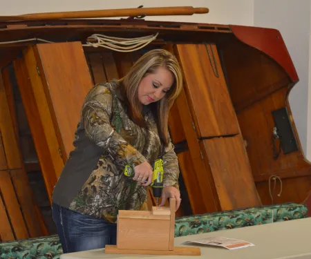 A woman attaches the predator guard to a wooden nest box. 