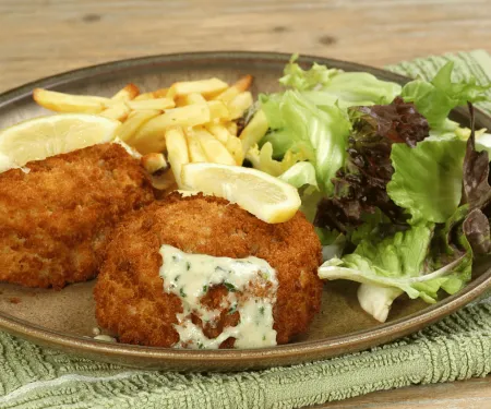A plate with a couple of fish cakes, and a salad.