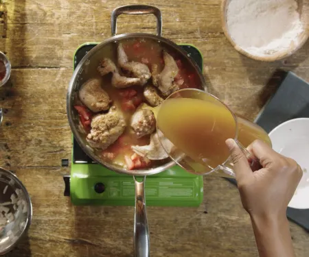Broth is being poured over a pan of Rabbit Cacciatore