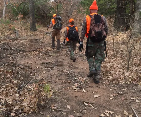 three people hunting in the woods 