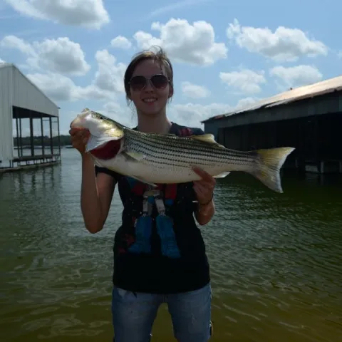 Young girl holding striped bass.