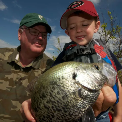 Man and boy admire caught crappie.