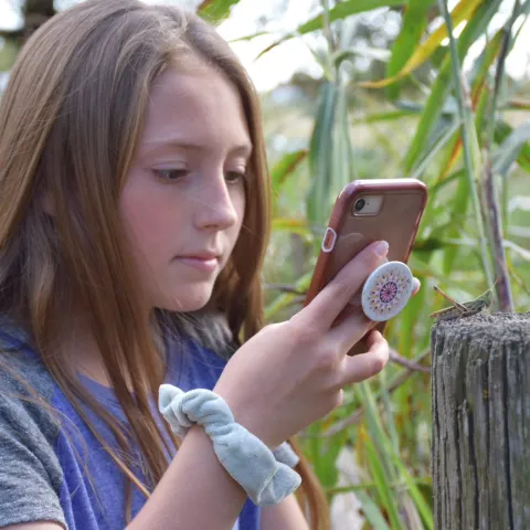 Girl with phone taking pictures of wildlife.