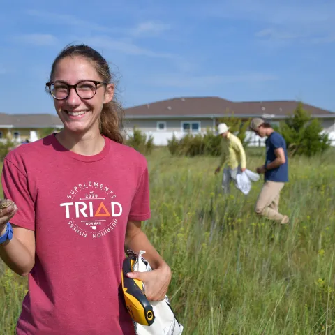Woman holds a texas horned lizard in a field.