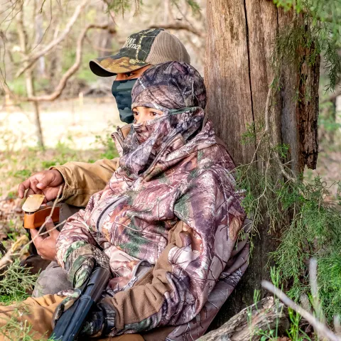 Two turkey hunters sitting under a tree.  Photo by Kelly Adams