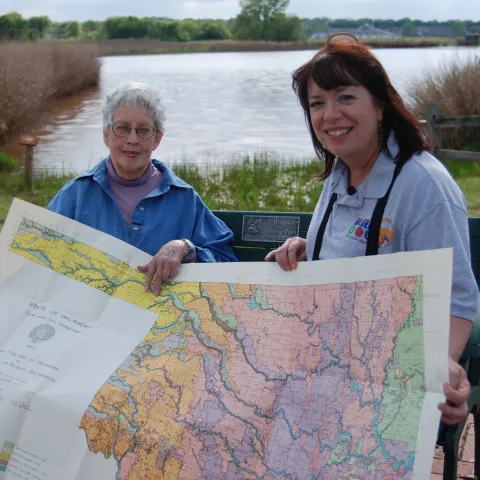 Two women sit on a bench with a map of Oklahoma