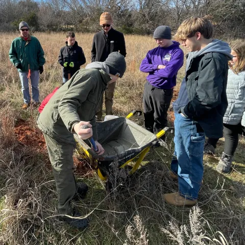 Scouts pour concrete into a hole that will serve as the base of a bat box mounted on a pole.