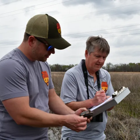 Two biologists look at a small turtle and record its location. 