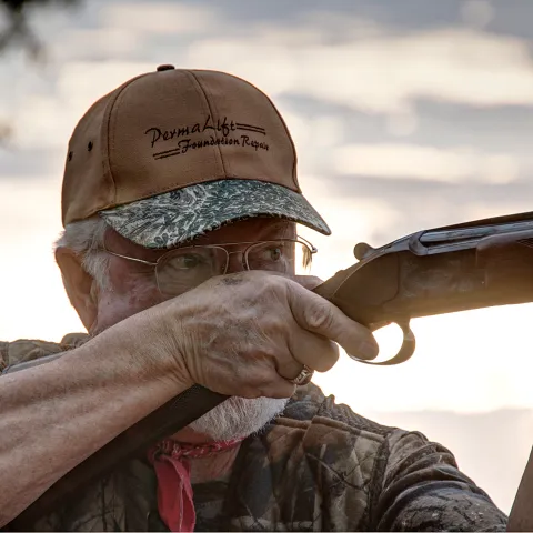 A man holds a shotgun. 