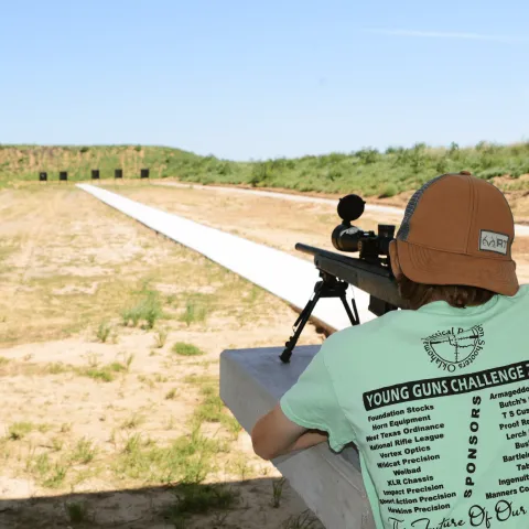 A male teenager is photographed from behind as he aims his rifle down the Packsaddle WMA shooting range.