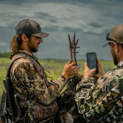 Two men are checking in their harvest turkey after a hunt.