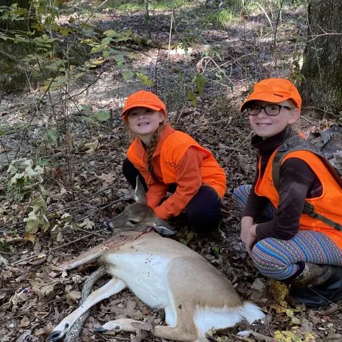 2 young girls with harvetsed doe