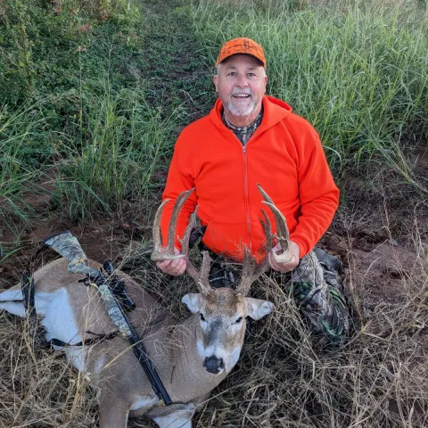 Hunter wearing orange pictured with a harvested deer.