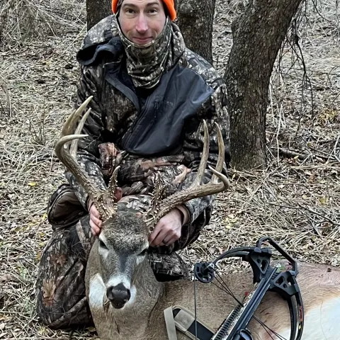 Hunter wearing orange pictured with a harvested deer.