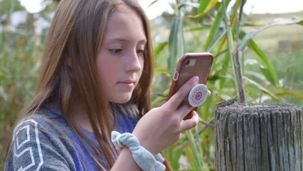 Girl with phone taking pictures of wildlife.