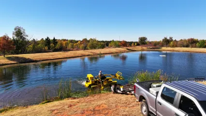 A fisheries employee of the Oklahoma Department of Wildlife Conservation is using a WeeDoo to maintain a Close To Home Fishing pond at Mitch Park.