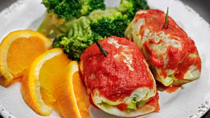 Dinner plate containing broccoli, oranges, and venison cabbage rolls