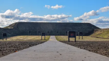 A view straight down the brand new 100-yard rifle range at Copan WMA. Several targets are visible. A concrete path leads to the large berm at the back of the range..