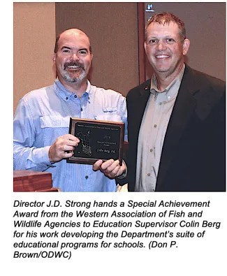 Director J.D. Strong hands a special achievement award from the Western Association of Fish and Wildlife Agencies to Education Supervisor Colin Berg for his work developing the Department's suite of educational programs for schools (DON P. BROWN/ODWC)