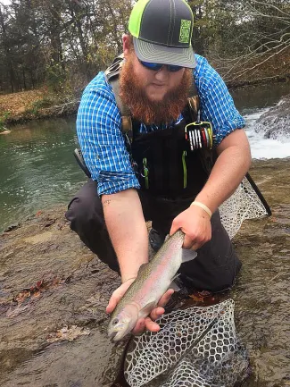 Angler Woodrow Barnes holds a rainbow trout he caught at the Blue River Public Fishing and Hunting Area last year. Trout stocking will begin by Nov. 1 at six seasonal fishing areas across the state. (Doron Lovett via Facebook)