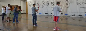 Educators shooting bowfishing equipment at an Explore Bowfishing training with net and targets in the background.