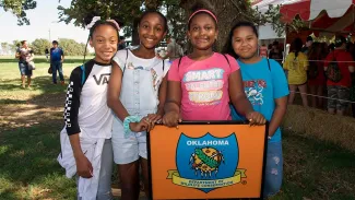 A group of young girls standing in front of a agency logo at Wildlife EXPO.