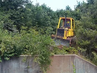 Wildlife Department heavy equipment operator Jay Barfield clears brush and trees from the spillway at Lake Nanih Waiya. (Don Groom/ODWC)