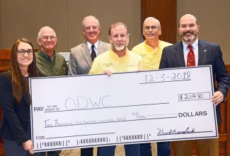 Gathered for a donation from the Oklahoma Striped Bass Association are, from left, Wildlife Department Fisheries Biologist Ashley Nealis, Ed Wampler of OSBA, Department Fisheries Chief Barry Bolton, David Langford of OSBA, Jerry Sikes of OSBA, and Department Director J.D. Strong. (Don P. Brown/ODWC)