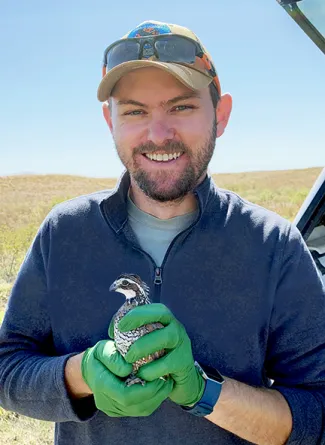 Biologist Tell Judkins holding a quail 