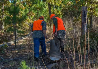 Two people pull a harvested buck out of the woods from Skiatook Lake.