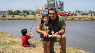 Father and daughter with catfish at family fishing event.