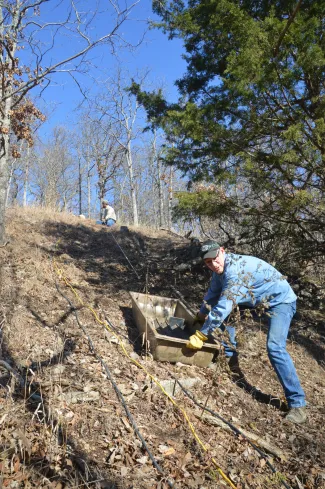 Biologist transport materials down hill for iron gate.
