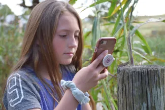 Girl with phone taking pictures of wildlife.