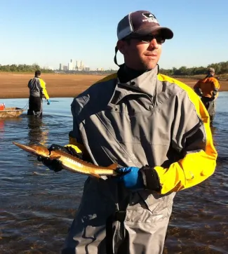 Biologist Superstar Josh Johnston holds a sturgeon in the Arkansas River near downtown Tulsa.